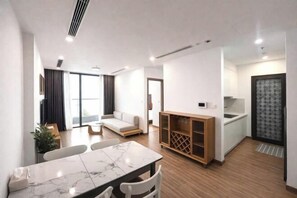 Una sala de estar moderna con sofá, mesa de comedor y zona de cocina.