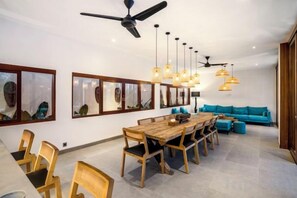 A modern dining area with a wooden table and chairs, ceiling fans, and pendant lights. - Villa Pool Bar by BaliSuperHost (Bali)