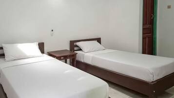 A room with two single beds, a wooden nightstand, and a green door.