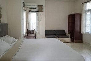 Un dormitorio con cama, escritorio, silla, sofá y estantería.