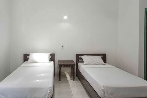 A twin room with two single beds, a small bedside table, and a light fixture on the ceiling. - Daton House Near Bali Zoo Ubud Mitra RedDoorz (Bali)