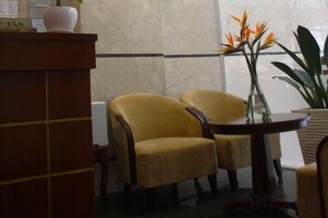 A reception area with a wooden desk, two yellow armchairs, and a vase with flowers. - Ohana Hotel - Near Bitexco (Ho Chi Minh City)