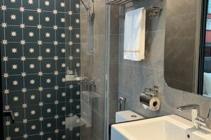 A bathroom with a shower, a sink, and a towel hanging on the wall. - Ohana Hotel - Near Bitexco (Ho Chi Minh City)