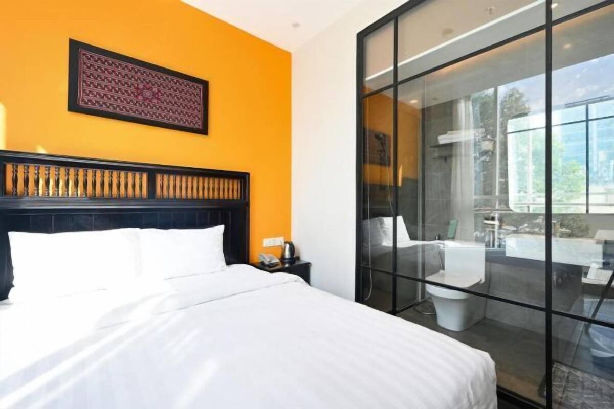 Une chambre d’hôtel comprenant un lit, une table de chevet, une œuvre d’art accrochée au mur et une porte-fenêtre coulissante donnant sur un espace extérieur.