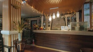 Zona de recepción con mostrador de madera, una planta en maceta y un extintor.