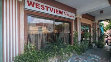 Fachada do Westview Pension com grandes janelas, entrada em azulejo e plantas em vasos.