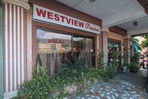 Façana d'un edifici Westview Pension amb grans finestres, entrada enrajolada i plantes en testos.