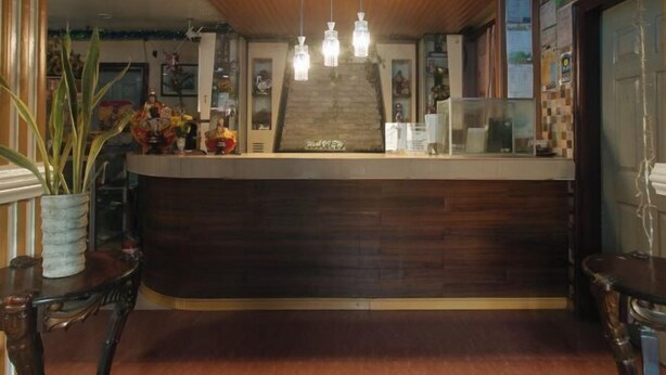 Zona de recepción con mostrador de madera, lámparas colgantes y una escalera que conduce a un nivel superior.