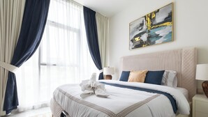 A hotel room with a large bed, a bedside table, a lamp, and a painting on the wall. - SIMPLY COMFORT Chic 3 Br Apartment with Private Pool (Dubai)
