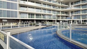 A multi-story hotel with a central swimming pool, balconies on each floor, and a clear sky. - SIMPLY COMFORT Chic 3 Br Apartment with Private Pool (Dubai)