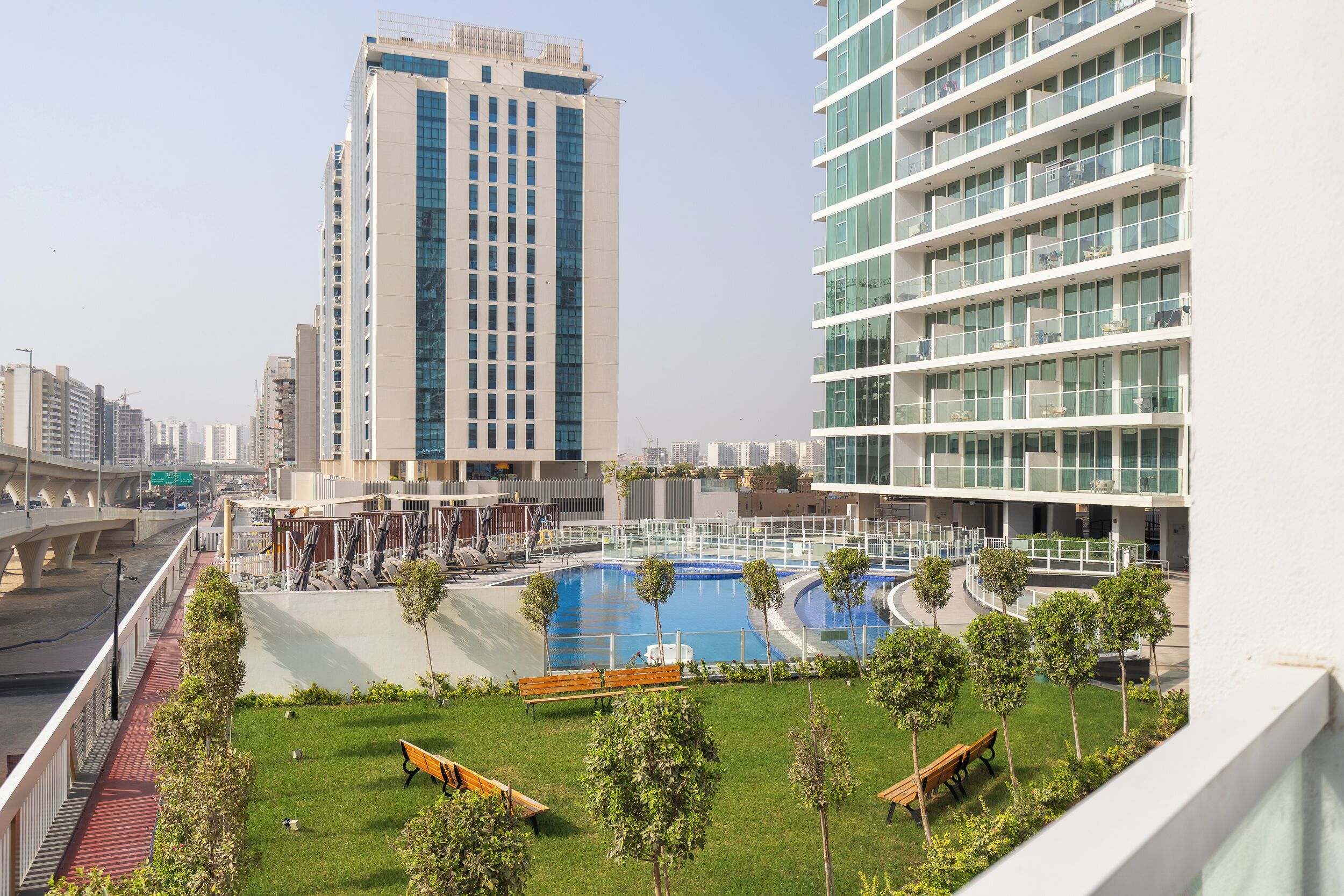A modern building with a rooftop pool, surrounded by greenery and benches.