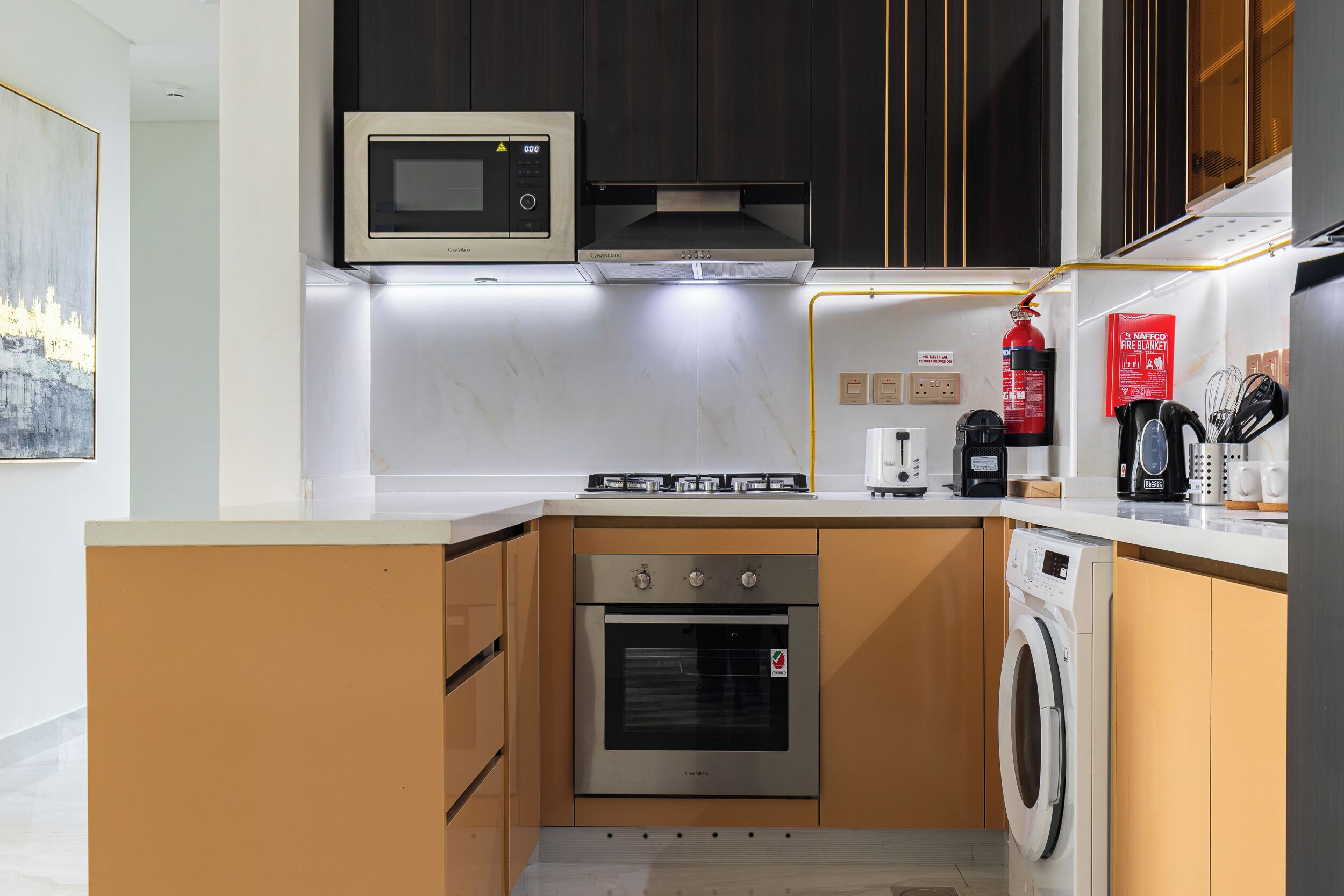 A compact kitchen with a microwave, stove, oven, and washing machine.