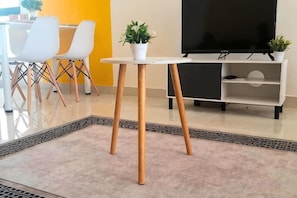A modern living room with a white table, two potted plants, a flat-screen TV, and a dining area with white chairs. - Core Soho Suite KLIA FREE WIFI BY GOLDEN GATES (Dengkil)