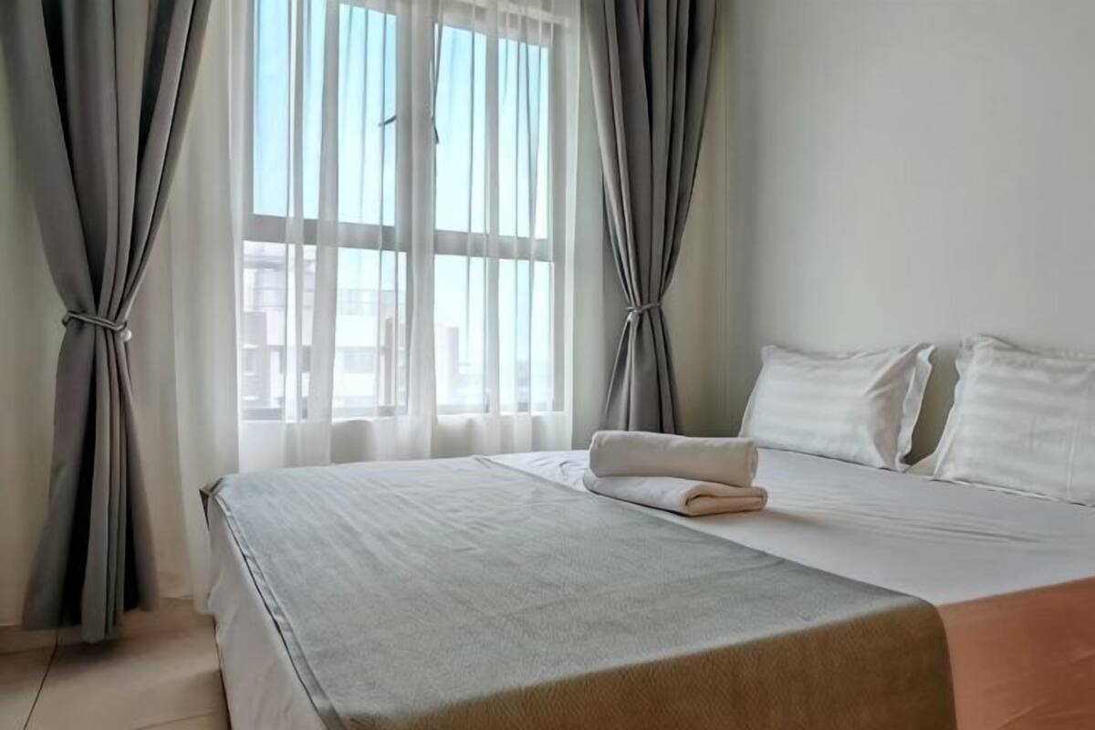 A hotel room with a bed, curtains, and a window.