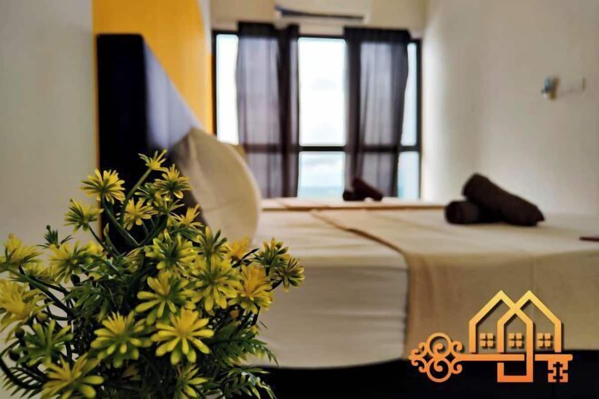 A hotel room with a bed, a potted plant, and a window with curtains.