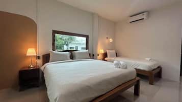 A hotel room with a large bed, two bedside tables, a window, and an air conditioning unit.