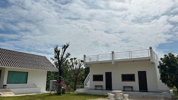 A modern two-story building with a flat roof, a covered outdoor seating area, and a gravel driveway.