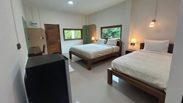 Une chambre d’hôtel avec deux lits, un bureau et une fenêtre donnant sur un espace verdoyant.