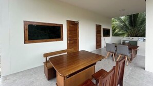 Un coin repas avec une table et des chaises en bois, une grande fenêtre et une vue sur un palmier.