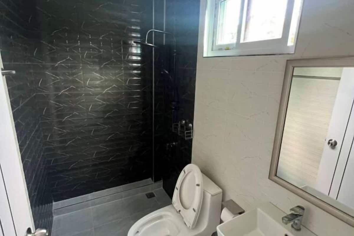 A bathroom with a shower, toilet, sink, and a mirror.