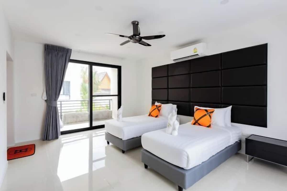Une chambre d’hôtel moderne avec deux lits, un ventilateur de plafond et une grande fenêtre donnant sur un beau paysage.