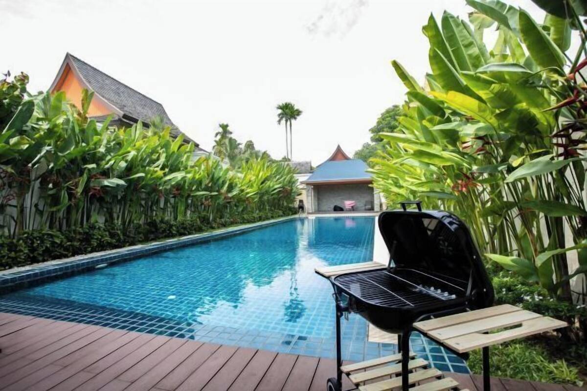 Une piscine avec un barbecue et une terrasse en bois.