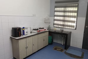 A small kitchen with a sink, stove, and cabinets. - Homestay Samera (Kapar)