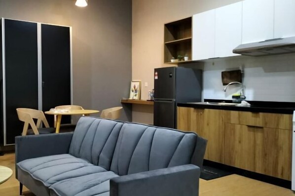 A compact kitchen with a sofa, a dining table, and a refrigerator. - Mahkota Valley Suite Indera Mahkota@ Netflix (Kuantan)