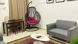 A living room with a grey sofa, a hanging chair with pink cushions, a wooden dining table with chairs, and a patterned rug. - Fallem's Homestay I 4 Rooms I Fully Aircond I WiFi (Melaka)