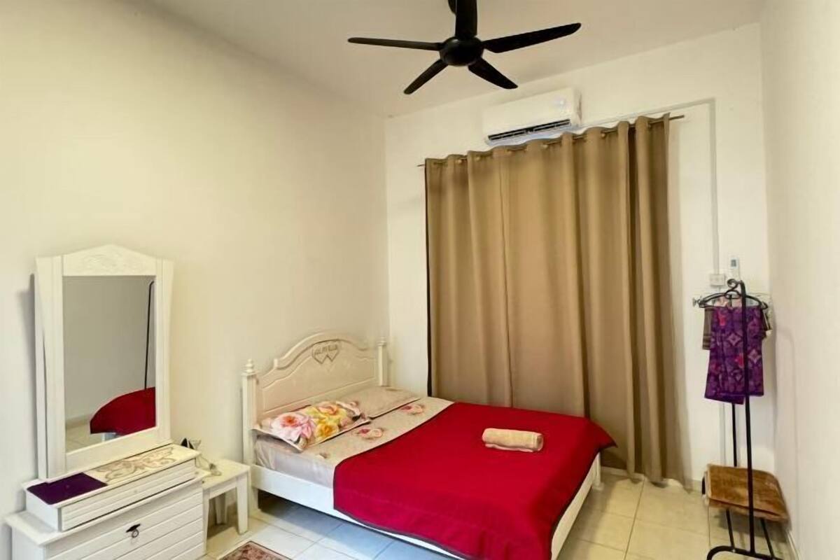 Une chambre à coucher comprenant un lit, une commode, un miroir, un ventilateur de plafond et une fenêtre avec des rideaux.