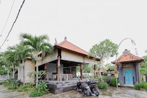 A traditional building with a tiled roof, a covered porch, and a small adjacent structure with a blue door. - The Lavana Jhonny Kibung Villas Lembongan (Bali)