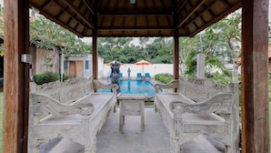 A covered outdoor area with a pool, benches, and a table. - The Lavana Jhonny Kibung Villas Lembongan (Bali)