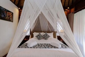 A bed with a canopy, pillows, and a patterned bedspread.