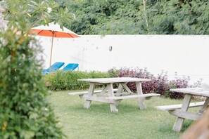 Ein Patio im Freien mit Picknicktischen und blauen Lounge-Stühlen.