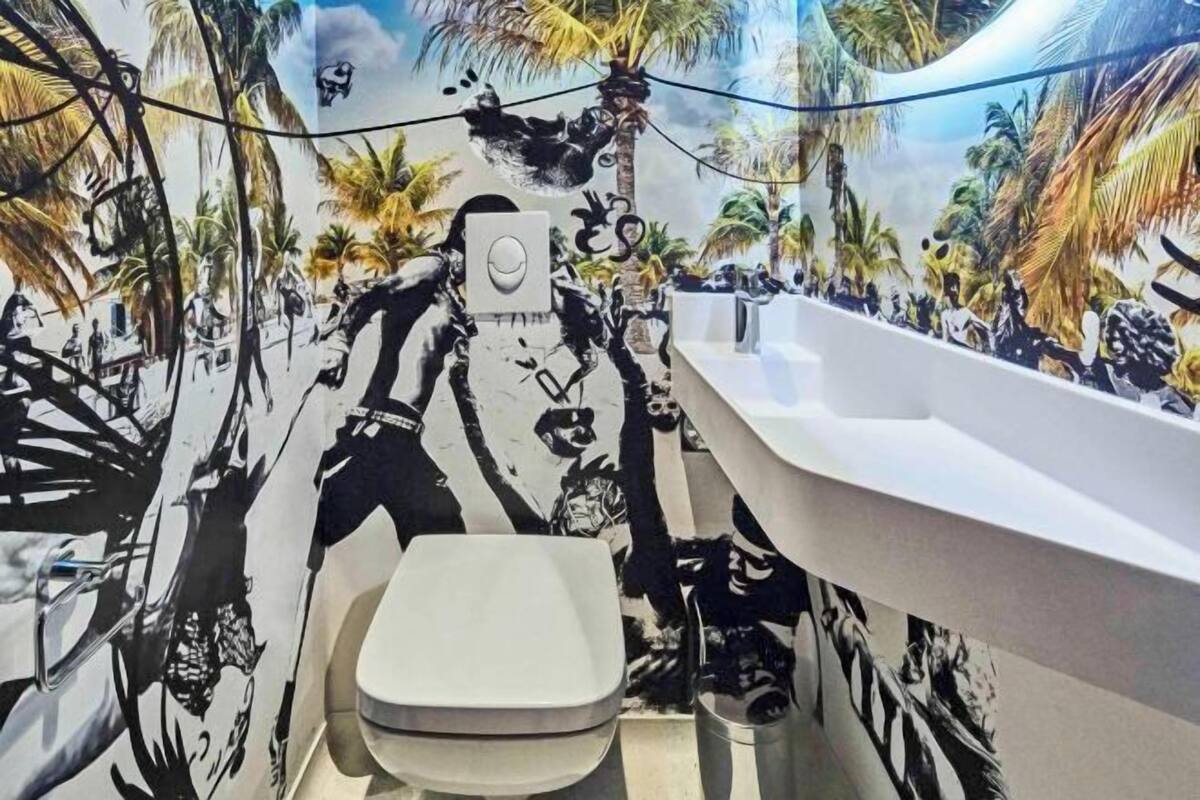 Un baño con un mural de una playa, un inodoro y un lavabo.