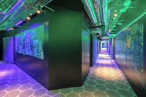 A hallway with a patterned floor, green and purple lighting, and a mural on the walls. - JO&Joe Paris Gentilly - Auberge de Jeunesse (Gentilly)