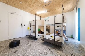 Ein Zimmer mit Etagenbetten, einem gemusterten Boden und einer Holzbalkendecke.