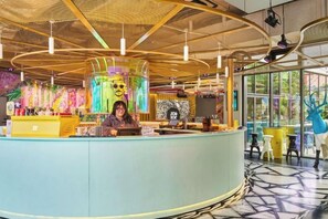 Ein modernes Interieur mit einer gebogenen Rezeption, einer großen digitalen Anzeige und einer Decke mit hängenden Leuchten.
