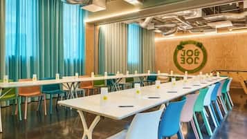 A conference room with a long table, colorful chairs, and a logo on the wall.