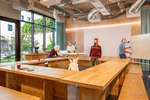 Une salle de réunion moderne, dotée de tables en bois, d’un tableau blanc et de grandes fenêtres.