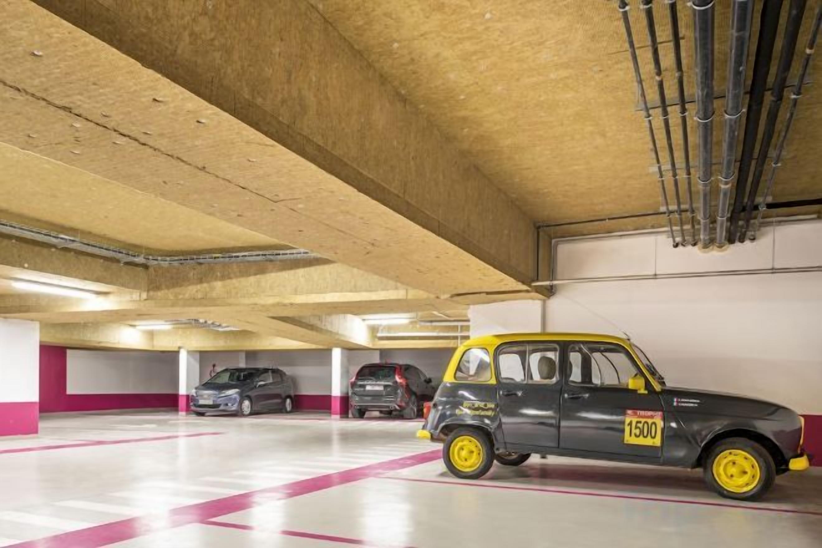 A parking garage with multiple cars, including a distinctive yellow and black car with the number 1500.