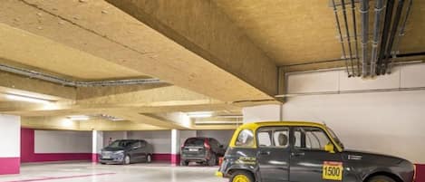 A parking garage with multiple cars, including a distinctive yellow and black car with the number 1500.