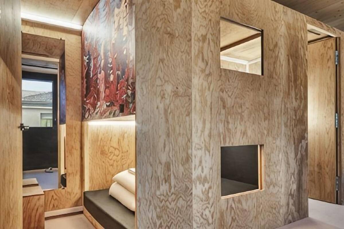 Una habitación con paneles de madera, un ventanal pequeño y un banco empotrado.