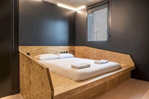 Un dormitorio moderno con cama de madera, una ventana y un banco empotrado.