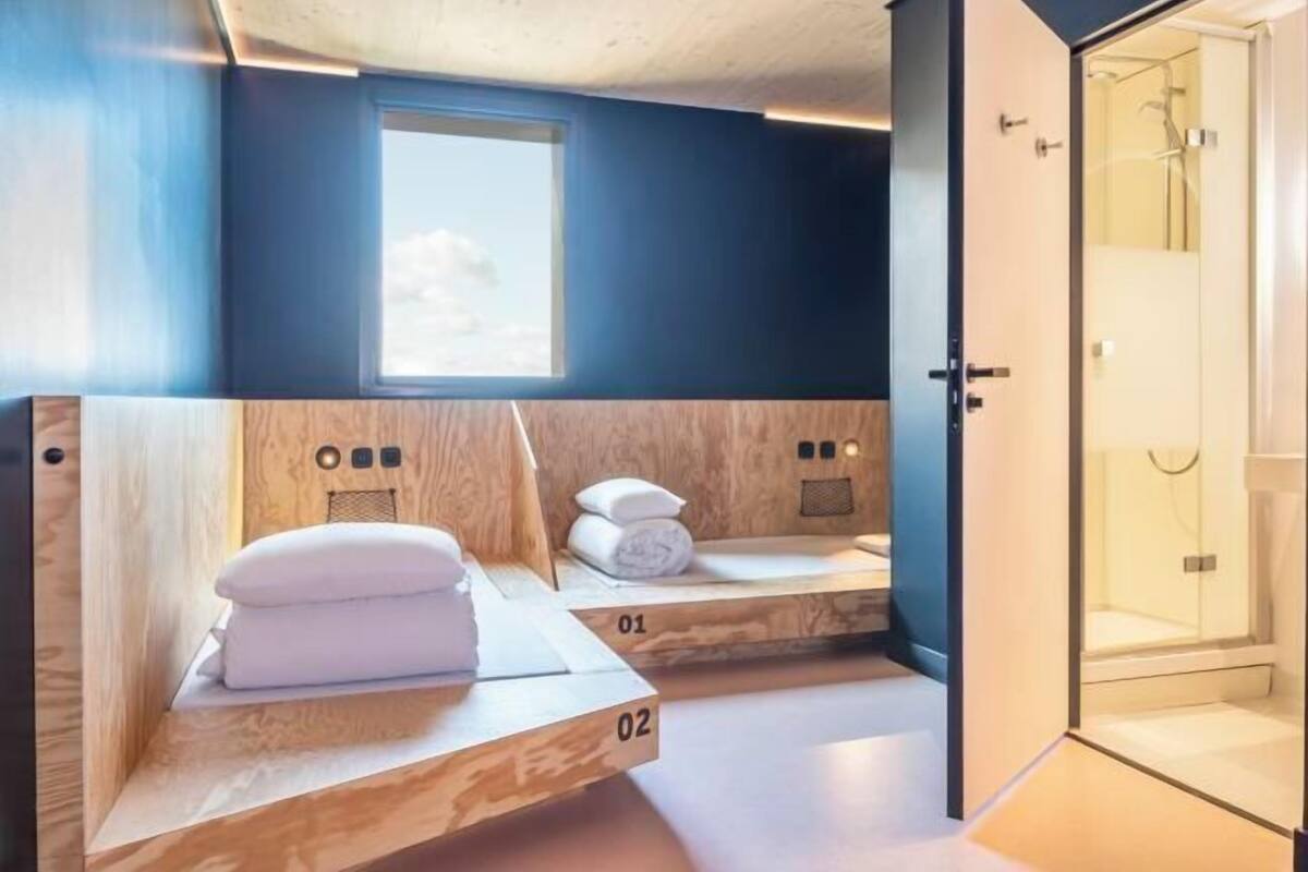 Un spa moderno con dos bancos de madera, un box de ducha de vidrio y un ventanal amplio.