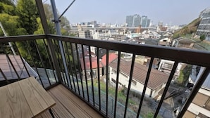 A balcony with a view of a cityscape, a wooden table, and a metal railing. - Relaxing ishikawa-cho (Whole house/Good view/sauna/2LDK) (Yokohama)
