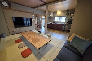 A living room with tatami flooring, a low wooden table, and a sofa with cushions. - Relaxing ishikawa-cho (Whole house/Good view/sauna/2LDK) (Yokohama)