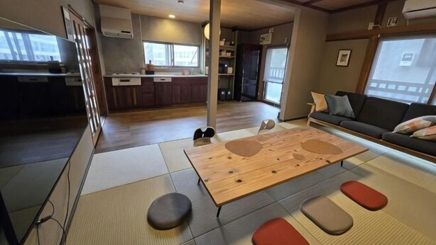 A modern interior with a tatami mat, a sofa, and a kitchen in the background. - Relaxing ishikawa-cho (Whole house/Good view/sauna/2LDK) (Yokohama)