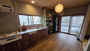 A kitchen with wooden cabinets, a built-in oven, and a window overlooking a balcony. - Relaxing ishikawa-cho (Whole house/Good view/sauna/2LDK) (Yokohama)