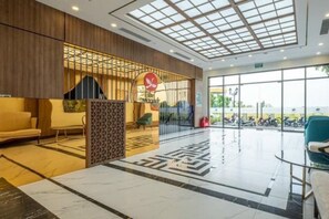 A hotel lobby with a reception desk, seating area, and large windows. - Sunshine Apartment - Vinhomes Ocean Park Ha Noi (Hanoi)